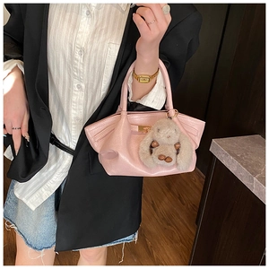 Détail d'un sac à main en cuir rose clair avec boucle en métal et breloque lapin