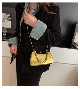 Detail of gold acrylic mirror clutch bag with spherical metal handle and chain strap