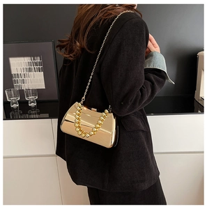 Detail view of a gold mirror-finish evening bag with large metal bead handle