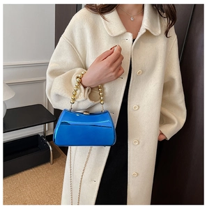 Close-up of royal blue acrylic clutch with golden bead handle and metallic chain strap
