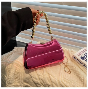 Detailed view of magenta acrylic clutch bag with golden beaded handle and chain strap