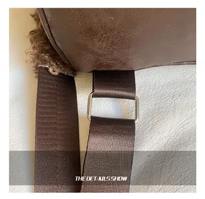 Detail of silver metal buckle connecting brown nylon strap to faux fur plush backpack