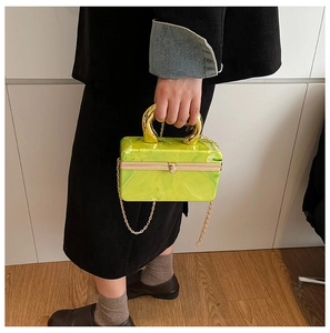 Detail of green acrylic marble box bag with golden U-handle and crossbody chain strap
