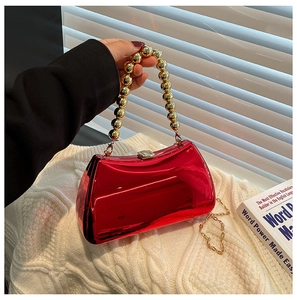 Detail of red acrylic evening bag with gold beaded handle and mirror metallic finish