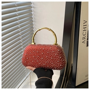 Detail of red rhinestone evening clutch with gold bamboo handle and metallic chain strap