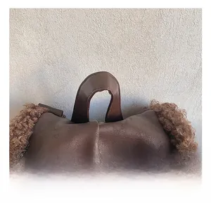 Detail of plush brown faux shearling backpack with wide leather handles and soft texture