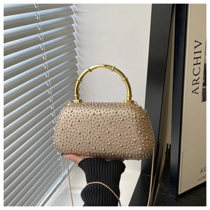 Detail of champagne gold rhinestone clutch with golden bamboo handle and chain strap