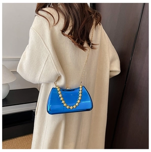 Blue metallic acrylic evening bag with gold bead handle shown on a beige coat