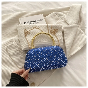 Close-up of navy acrylic clutch with silver rhinestones and gold bamboo-style handle