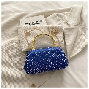 Detailed top view of royal blue evening bag with gold bamboo handle and metallic chain