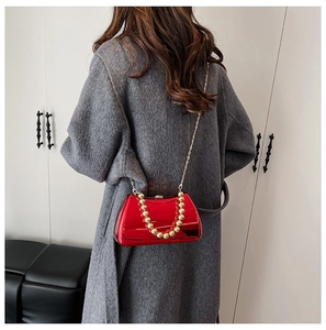 Red acrylic evening bag with gold beaded handle shown on model in grey coat
