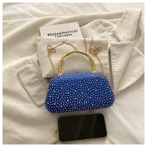 Macro view of sapphire blue rhinestone evening bag with bamboo texture gold handle
