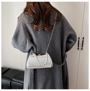 Detail of silver mirror evening clutch with beaded handle and metal chain strap