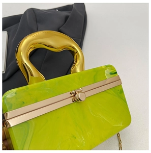 Detail of green marble acrylic clutch bag with sculptural gold handle and chain strap