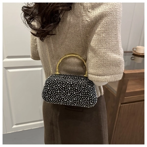 Close-up of sparkling rhinestone handbag with golden bamboo handle and chain strap on a model