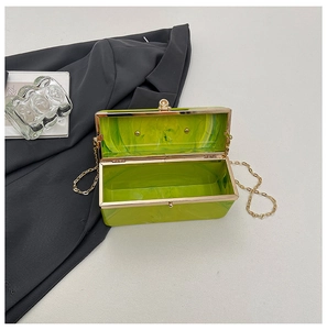 Macro view of neon green acrylic evening bag with marble texture and golden frame