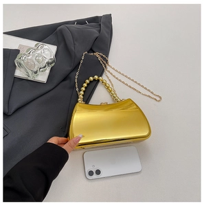 Detail of golden acrylic evening clutch featuring pearl handle and chain with phone reference