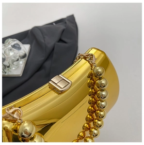 Detail shot of golden acrylic evening bag with metallic bead chain and snap closure