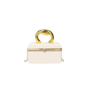 Macro detail of white acrylic box bag featuring a unique sculptural gold metal handle