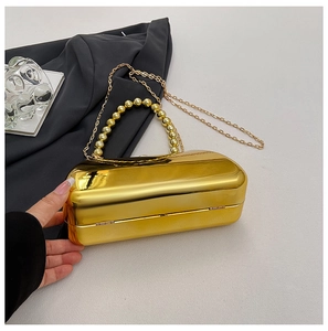 Close-up of gold mirror evening clutch with pearl handle and fine chain shoulder strap