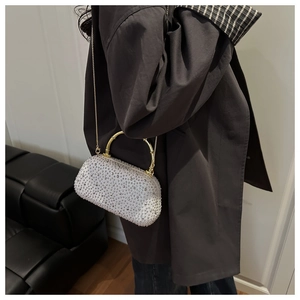 Close-up of sparkling rhinestone handbag with golden bamboo handle and chain strap