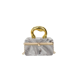 Detailed view of marble acrylic bag with a unique gold metal handle and chain strap