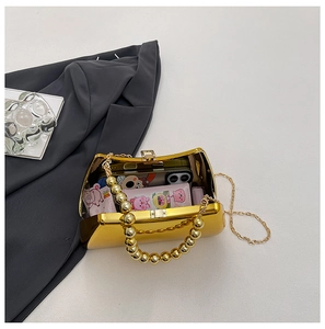 Detail of gold mirror acrylic evening bag showing inner storage for phone and tissue