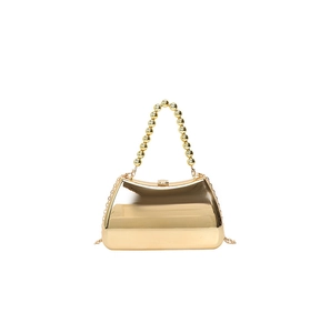 Close-up of golden acrylic evening bag with metallic mirror finish and beaded handle
