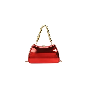 Macro shot of glossy red acrylic evening bag with gold beaded handle and metal chain