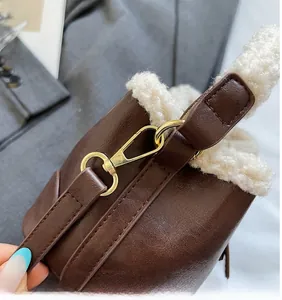 Détail du cuir synthétique marron avec bordure en laine bouclée et crochet métallique doré