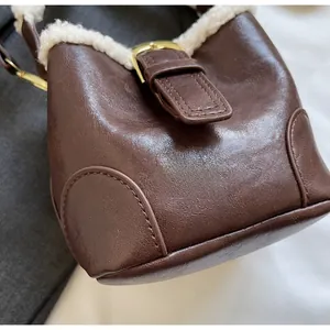 Gros plan du sac seau en similicuir marron avec bordure en peluche et boucle en métal doré
