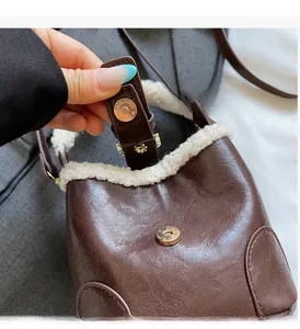 Vue détaillée de la boucle dorée magnétique et du bord en peluche du sac seau marron
