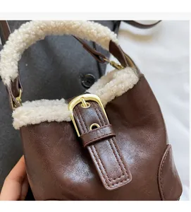 Détail du sac seau en similicuir marron avec bordure en laine d'agneau et boucle métallique dorée