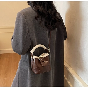 Détail d'un sac seau marron vintage avec garniture en fausse fourrure et boucle dorée