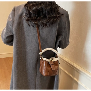 Mini sac seau en cuir marron avec bordure en fausse fourrure blanche sur manteau gris