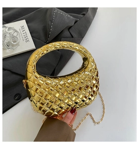 Close-up of golden acrylic evening bag with woven texture and metallic moon shape handle