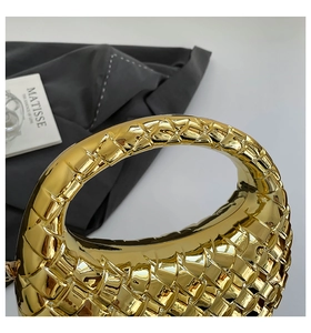 Close-up of golden woven pattern on a luxury evening bag with metallic glossy finish