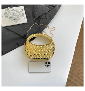 Detail of gold woven evening bag with chain strap shown next to phone for size reference