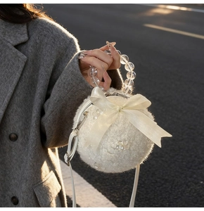 Close-up of white plush sphere bag with satin bow and transparent beaded handle detail