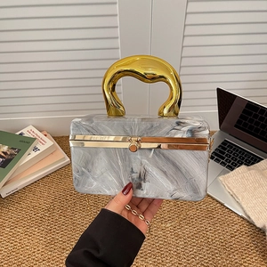 Modern acrylic marble clutch with a bold gold handle and elegant crossbody chain strap