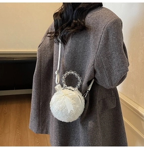 Detail of white plush sphere bag with beaded handle and silk bow on wool blazer