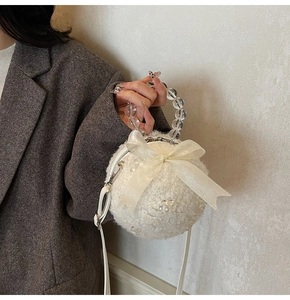 Detail view of white plush round bag with organza bow and acrylic beaded handle