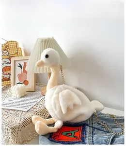 Détail du sac bandoulière en peluche cygne blanc avec chaîne dorée sur fond décoratif
