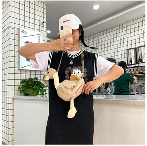 Détail d'un sac bandoulière cygne en peluche avec chaîne dorée porté par un mannequin