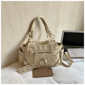 Detail of rivet strap and functional multi-pockets on beige bucket bag in office setting