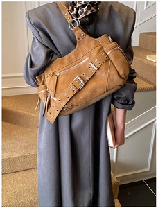 Close-up of caramel leather rivets motorcycle bucket bag worn with a gray wool coat