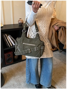 Detailed view of dark green suede bucket bag with metal studs and decorative zippers