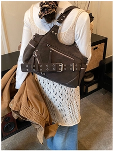 Detail of studded dark brown bucket bag with vintage belt strap on female model