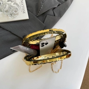 Golden acrylic evening clutch with wave texture, showing interior space for phone and makeup