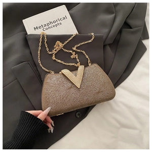 Detail of evening clutch with sparkling V-shaped rhinestone clasp and gold chain